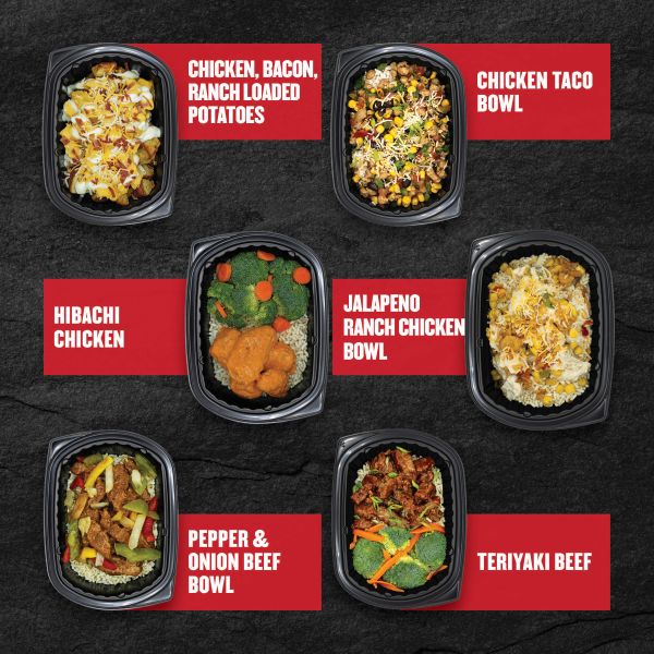 Six Clean Eatz Kitchen entrées on a black stone background — Chicken, Bacon, Ranch Loaded Potatoes; Chicken Taco Bowl; Hibachi Chicken; Jalapeño Ranch Chicken Bowl; Pepper & Onion Beef Bowl; and Teriyaki Beef — each shown in individual meal trays with red labels.