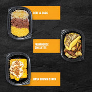 Three Clean Eatz Kitchen breakfast entrées on a black stone background — Beef & Eggs, Farmhouse Omelette, and Hash Brown Stack