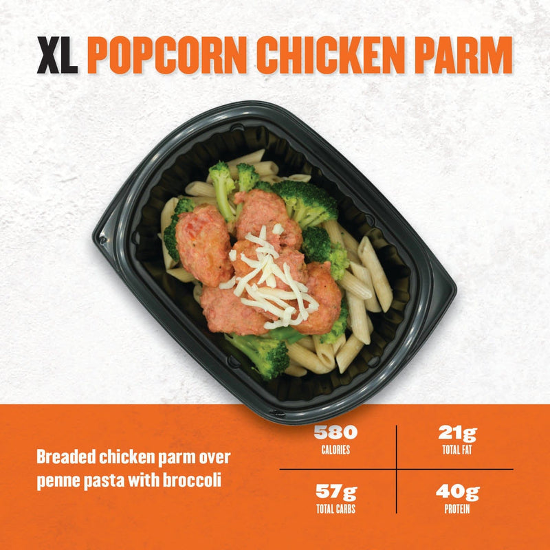XL Popcorn Chicken Parm – breaded chicken parmesan served over penne pasta with marinara sauce and broccoli in a black tray.