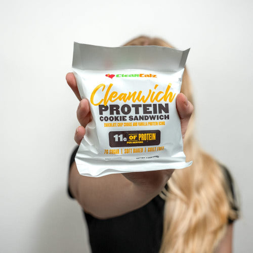 Person holding a Clean Eatz Cleanwich Protein Cookie Sandwich package against a white background