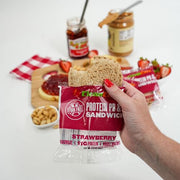 Images of someone eating a strawberry clean eatz peanut butter and jelly sandwich