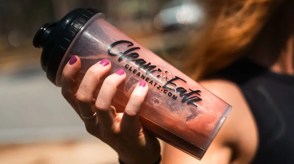 Woman holding protein shake bottle with pink liquid fitness drink
