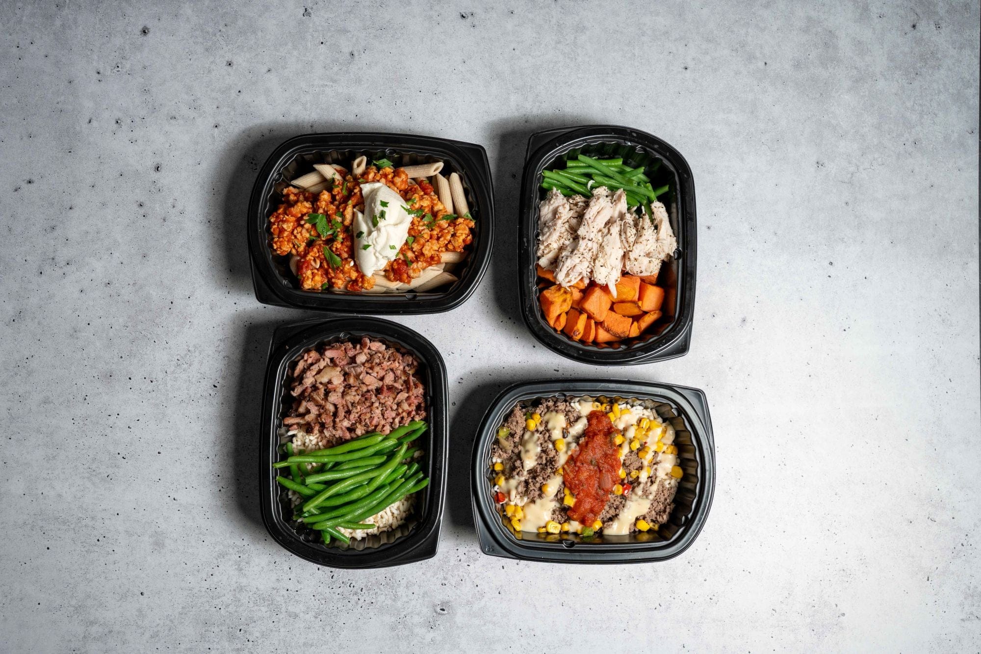 Four black containers of Clean Eatz Kitchen meals