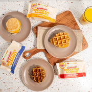 Waffles on plates with packets of breakfast sausage on a speckled countertop.