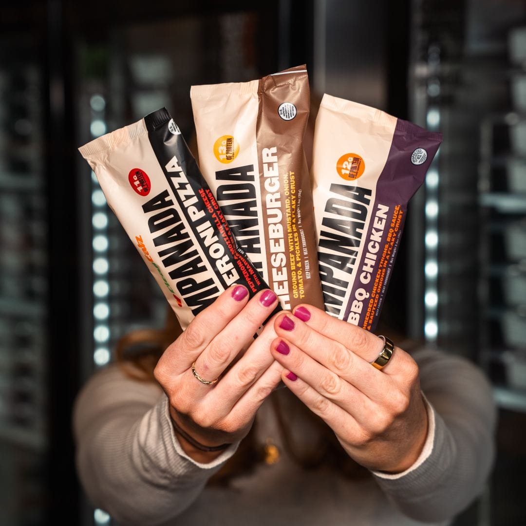 Hands holding three Clean Eatz new empanadas