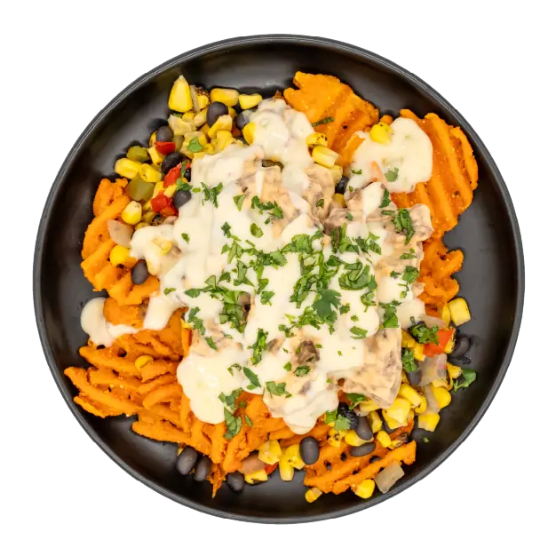 Adobo steak nachos with sweet potato waffle fries, corn, black beans, queso, and herbs on a black plate.