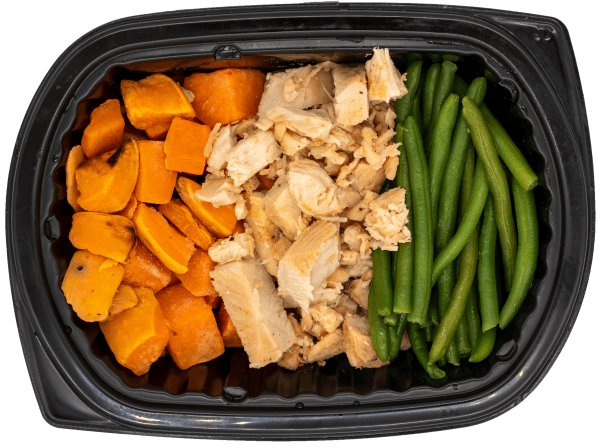 Chicken breast with green beans and roasted sweet potatoes in a black meal tray.