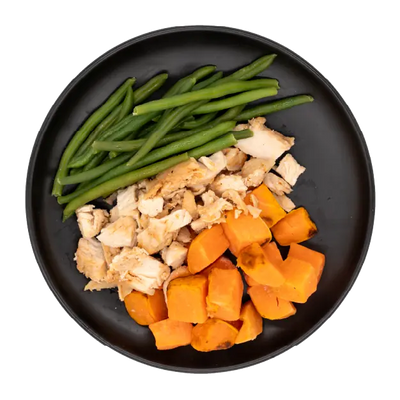 Chicken breast with green beans and roasted sweet potatoes on a black plate.