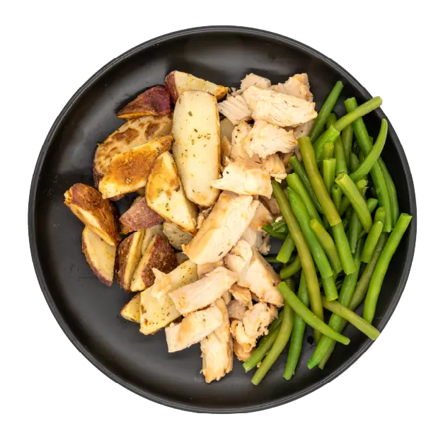 Diced chicken with green beans and roasted red potatoes on a black plate.
