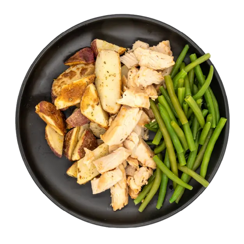 Diced chicken with green beans and roasted red potatoes on a black plate.