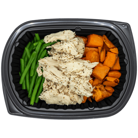 Smoked turkey breast with green beans and roasted sweet potatoes in a black meal tray.
