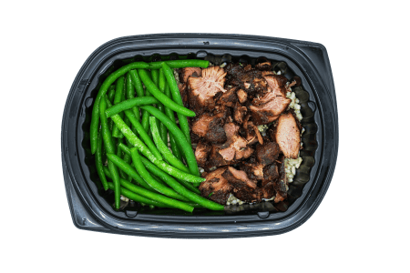 Chopped turkey burnt ends with green beans over rice in a black meal tray.