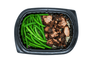 Chopped turkey burnt ends with green beans over rice in a black meal tray.