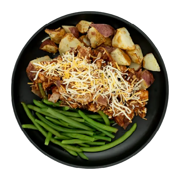 BBQ chicken topped with shredded cheese and bacon, served with green beans and roasted red potatoes on a black plate.