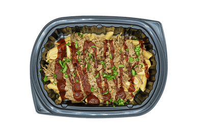 Prepared dish with meat and vegetables in a black plastic container on a green background