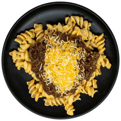 Shredded BBQ beef over creamy mac and cheese topped with shredded cheese on a black plate.