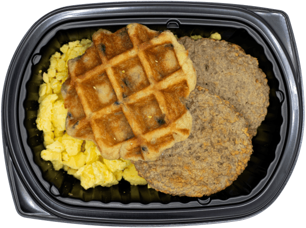 Blueberry waffle with scrambled eggs and turkey sausage in a black meal tray.