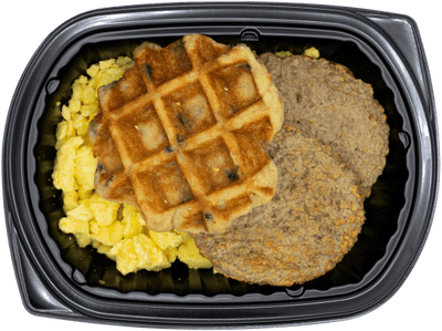 Blueberry waffle with scrambled eggs and turkey sausage in a black meal tray.
