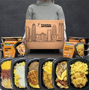 Person holding a 'Clean Eatz Kitchen' box with breakfast meal plan meals