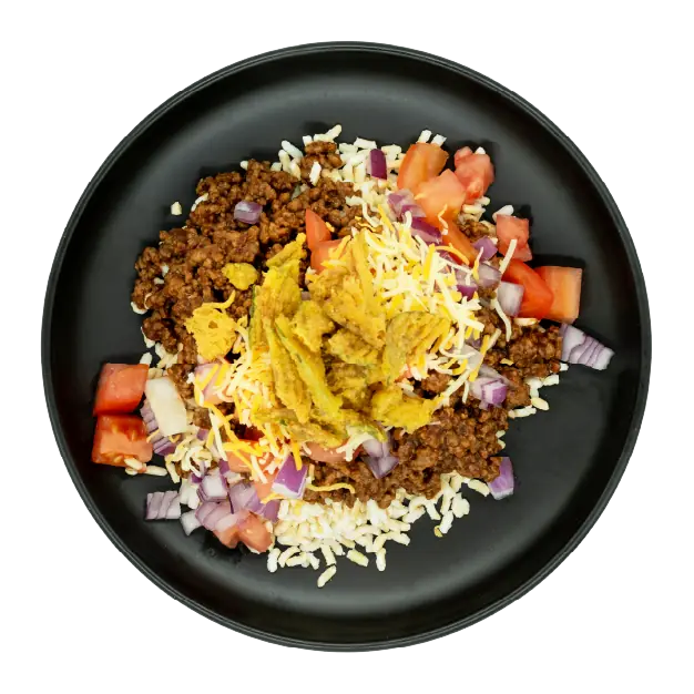 Cheeseburger bowl with ground beef, rice, shredded cheese, tomatoes, red onions, and pickles on a black plate.