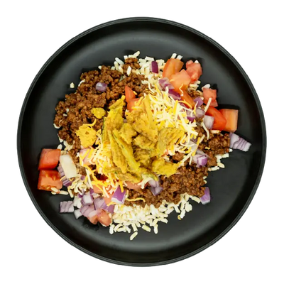 Cheeseburger bowl with ground beef, rice, shredded cheese, tomatoes, red onions, and pickles on a black plate.