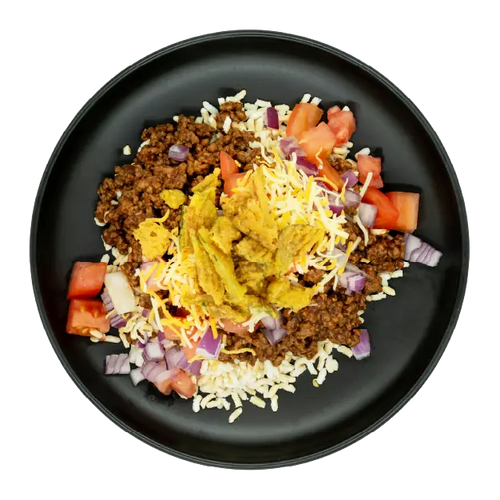 Cheeseburger bowl with ground beef, rice, shredded cheese, tomatoes, red onions, and pickles on a black plate.