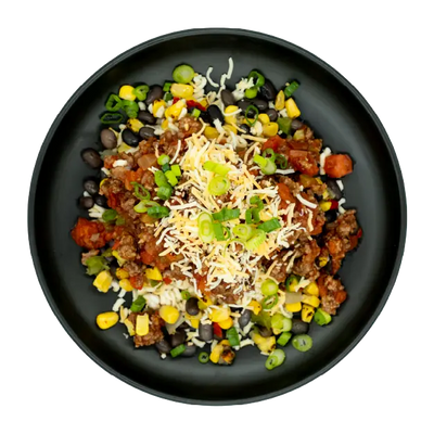 Chicken taco bowl with corn, black beans, salsa, shredded cheese, and green onions over rice on a black plate.