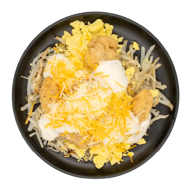 Scrambled eggs with hash browns, chicken bites, gravy, and shredded cheese on a black plate.