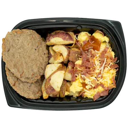 Turkey sausage patties with roasted red potatoes, scrambled eggs, gravy, shredded cheese, and bacon in a black meal tray.