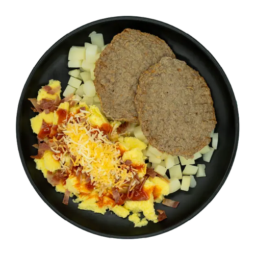 Turkey sausage patties with scrambled eggs, diced potatoes, shredded cheese, bacon, and gravy on a black plate.