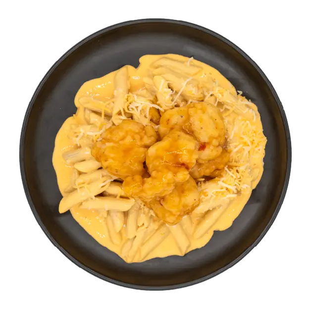 Hot honey chicken over mac and cheese topped with shredded cheese on a black plate.