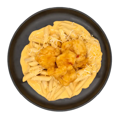 Hot honey chicken over mac and cheese topped with shredded cheese on a black plate.