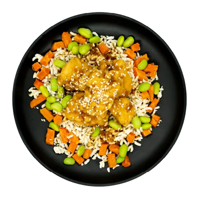 Korean BBQ chicken bites over rice with edamame and carrots on a black plate.