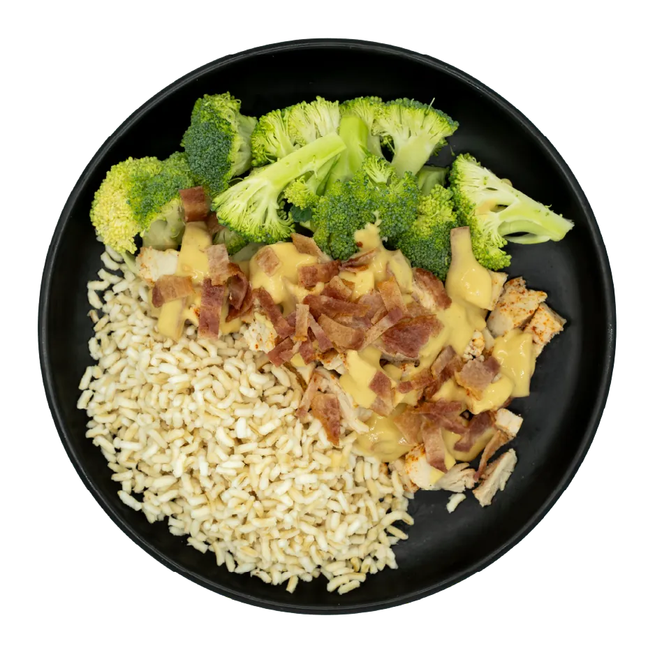 Chicken topped with maple sauce and crispy bacon, served with broccoli and brown rice on a black plate.