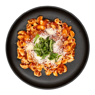 Meatballs in marinara sauce over pasta topped with grated parmesan and basil on a black plate.