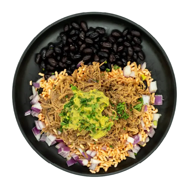 Mojo pork bowl with black beans, rice, red onions, and guacamole on a black plate.