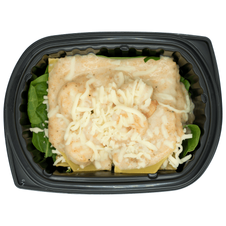Shrimp alfredo lasagna in a black meal tray with creamy white sauce, lasagna noodles, spinach, and shredded mozzarella.