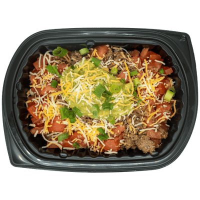 Burrito bowl topped with salsa, shredded cheese, guacamole, and green onions in a black meal tray.