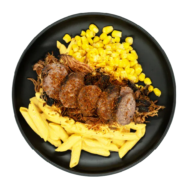 BBQ pulled pork with sliced sausage, corn, and mac and cheese on a black plate.
