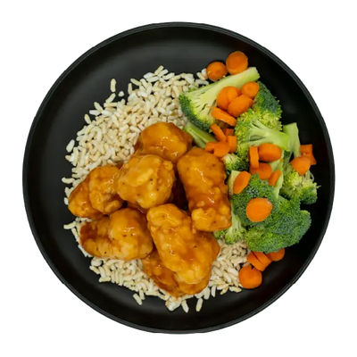 Sweet and sour chicken with broccoli, carrots, and brown rice on a black plate.