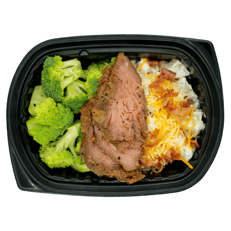Tri-tip steak with broccoli and loaded mashed potatoes topped with shredded cheese and bacon in a black meal tray.