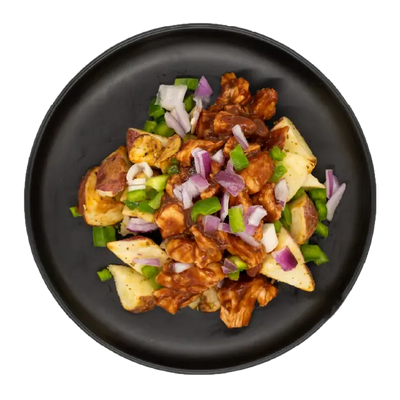 BBQ chicken with peppers and onions over roasted red potatoes on a black plate.