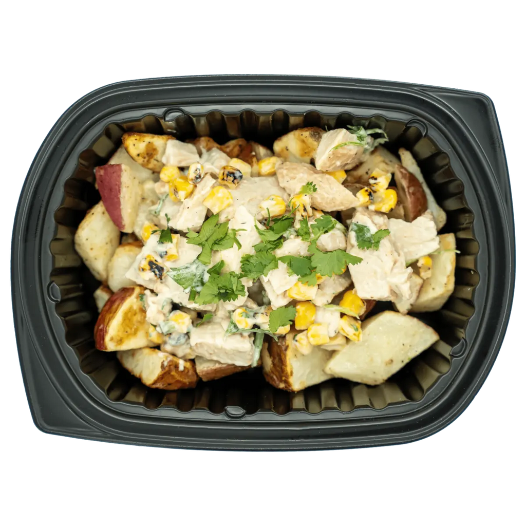 Prepared dish with potatoes, chicken, corn, and herbs in a black container on a white background