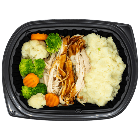Roasted turkey with gravy, mashed potatoes, and mixed vegetables in a black meal tray.