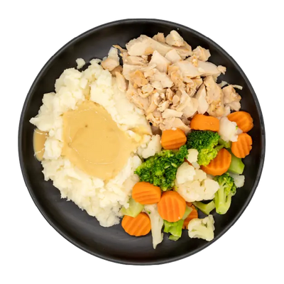 Roasted turkey with gravy, mashed potatoes, and mixed vegetables on a black plate.