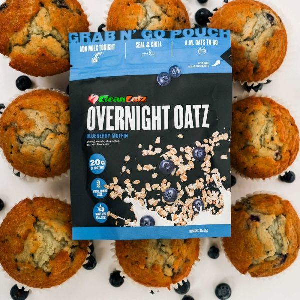 Clean Eatz Overnight Oatz Blueberry Muffin package surrounded by muffins and blueberries.
