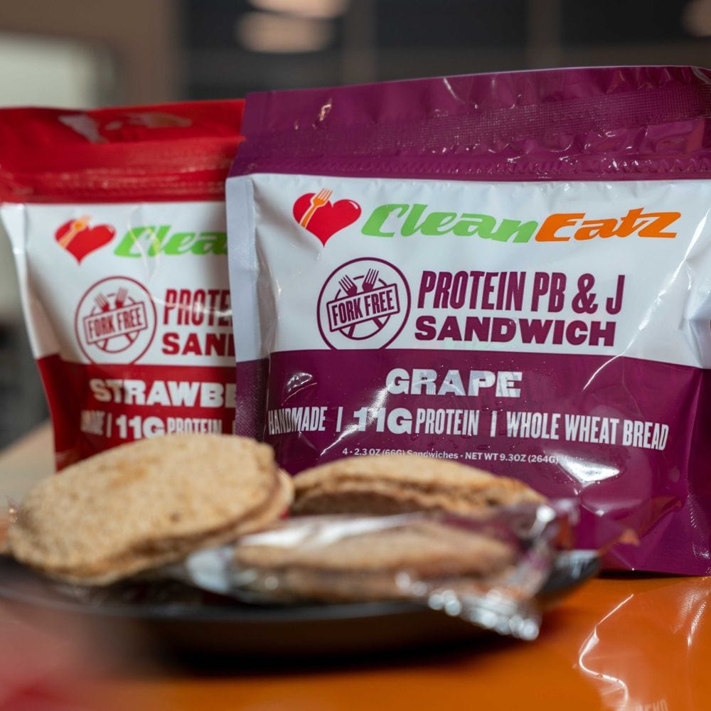 Two packages of CleanEatz protein snacks on a table with a blurred background