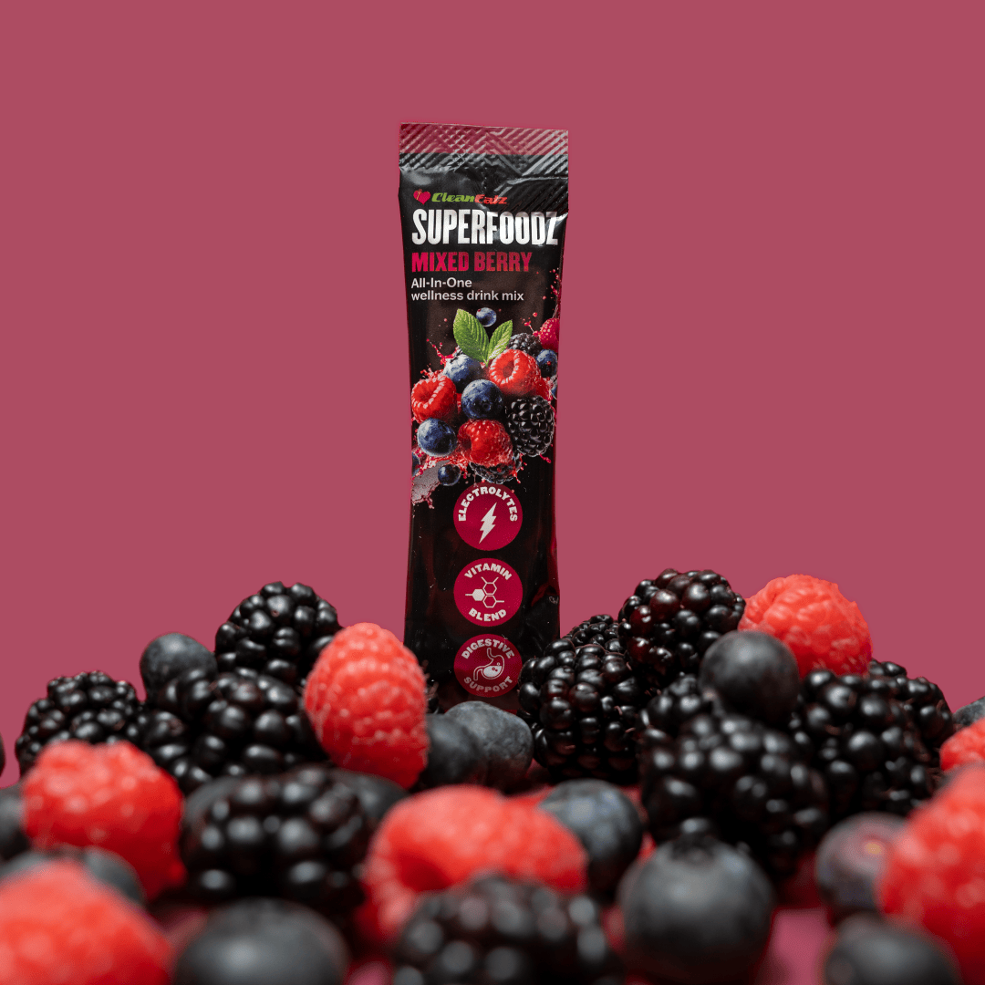 Superfood mixed berry drink mix package surrounded by blackberries and raspberries on a pink background